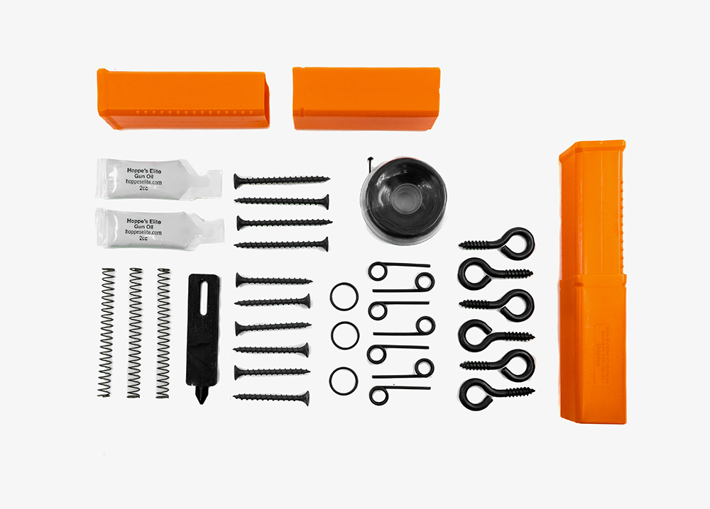 An array of essential accessories for the Fith Ops Perimeter Trip alarm laid out on a white background, including multiple screws, springs, trip wire, extra pins and small gun oil.