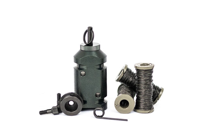 [The 12g perimeter trip alarm sitting on its flat bottom, next to the 308 adapter on its side, with 3 spools of military trip wire. Complete kit for camping, hiking, backpacking]]